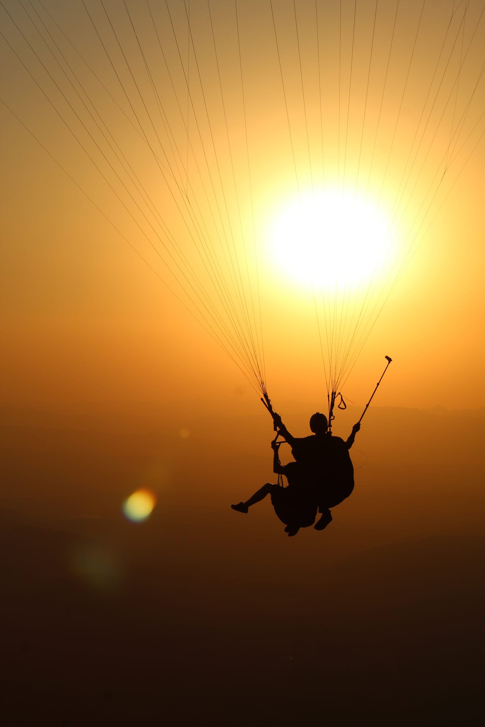 Parapente em silhueta contra o sol, sobre a Serra da Moeda